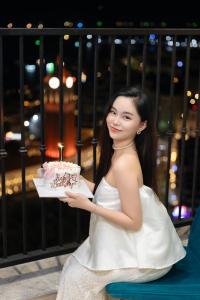 a woman in a white dress holding a birthday cake at The Hill Apartment - Phú Quốc - Firework & Ocean View in Phu Quoc