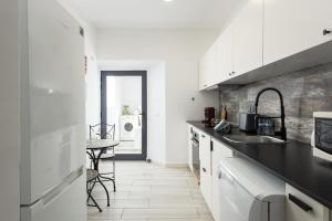 une cuisine avec des armoires blanches et un comptoir noir dans l'établissement Marggisa - City Center by HD, à Faro