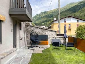 a patio with chairs and a grill on the side of a building at Mansarda Angel's Home in Ponte di Legno