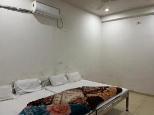 a bed in a room with a white wall at Hotel Shiv Mahima in Rīngas