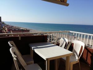 stół i krzesła na balkonie z widokiem na plażę w obiekcie Appartamento Ornella Al Mare w mieście Marotta