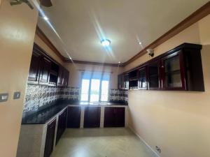 an empty kitchen with wooden cabinets and a window at Antique Family Residence in Kitala