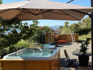 a hot tub under an umbrella in a yard at Chalet d hiver in Millau