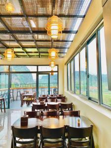 a dining room with tables and chairs and windows at Tam Coc Armany Hotel & Sky Restaurant in Vũ Lâm