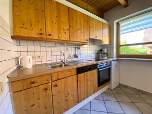 une cuisine avec des armoires en bois, un évier et une fenêtre dans l'établissement Natur Ferienpark 16 - Typ A, à Nieheim