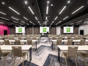 a conference room with tables and chairs and two screens at Ibis Styles Wroclaw Centrum in Wrocław
