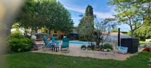 a backyard with a pool and chairs and a table at Reflet De PROVENCE dans cadre de verdure avec piscine chauffée in Le Thor