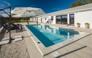 Una piscina con una sombrilla al lado de una casa. en Stunning Home In Zminj, en Jurići 29 fotos más