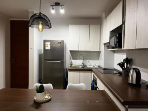a kitchen with a stainless steel refrigerator and a table at Departamento nuevo a 5 min de la playa 2D 2B in La Serena