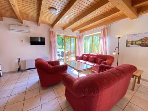 - un salon doté d'un mobilier rouge et d'une table en verre dans l'établissement Natur Ferienpark 28 - Ferienhaus Typ A, à Nieheim