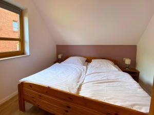 a bedroom with a bed with white sheets and a window at Haus 23 Natur Ferienpark - Gemütlicher Urlaubsort für entspannte Tage im Grünen und in der Nähe von den Externsteinen in Nieheim