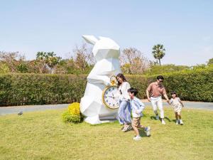 een gezin dat voor een klokbeeld loopt bij SO/ Sofitel Hua Hin in Cha Am
