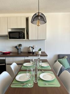 a dining room table with plates and wine glasses at Departamento nuevo a 5 min de la playa 2D 2B in La Serena