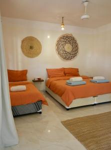 a bedroom with two beds with orange sheets at Al Hudu Mountain House - Jebel Shams in Al Ḩayl
