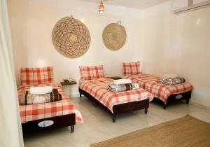 two twin beds in a room with red and white sheets at Al Hudu Mountain House - Jebel Shams in Al Ḩayl