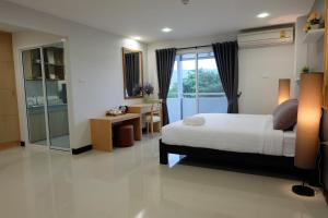 a bedroom with a bed and a desk and a window at Wisdom Residence in Hat Yai