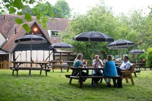a group of people sitting at a picnic table with umbrellas at The Poacher Inn in Hook