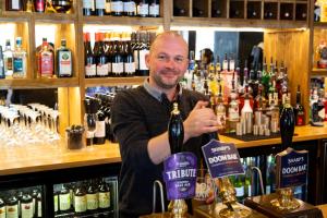 a man standing behind a bar holding a bottle of wine at The Poacher Inn in Hook +24 photos