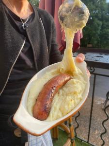 a person holding a hot dog in a bowl of food at Auberge Les Bastides 