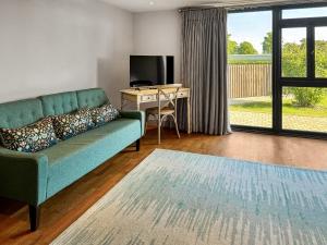 a living room with a green couch and a desk at Barn Owl Cottage - Uk48510 in Kirk Hammerton