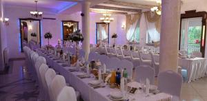 a banquet hall with white tables and white chairs at Zajazd pod Jarem in Bałtów
