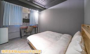 Un dormitorio con una cama y un escritorio con una computadora. en 新橙居-我們未與阿狗打訂房平台合作請勿在阿狗打訂房平台訂房, en Dalin