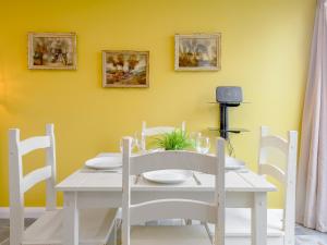 a white table and chairs in a room with a yellow wall at Dutch Barn Two - Uk12873 in Brynkir