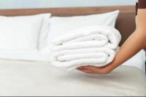 a woman is holding a stack of towels on a bed at UIM Mediterraneo Cendoya 2 Wifi in Puerto de Sagunto