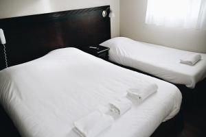 LimasにあるLogis Hôtel Novaの白いシーツが敷かれたホテルの部屋にベッドが2つある