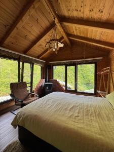 ein Schlafzimmer mit einem Bett und einem Stuhl und Fenstern in der Unterkunft Ayder Elizan Dağ Evleri in Çamlıhemşin