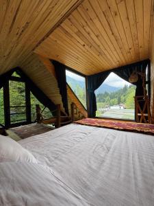 ein großes Bett in einem Zimmer mit einem großen Fenster in der Unterkunft Ayder Elizan Dağ Evleri in Çamlıhemşin