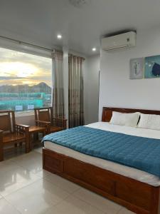 a bedroom with a bed and a table and a window at Manh Vuong Hotel &Travel in Cat Ba