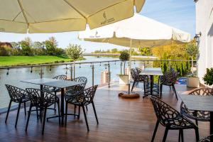 a patio with tables and chairs and a view of the water at Hotel Piast in Opole