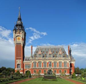 un grand bâtiment avec une tour d'horloge devant lui dans l'établissement Appartement cosy en centre-ville, à Calais
