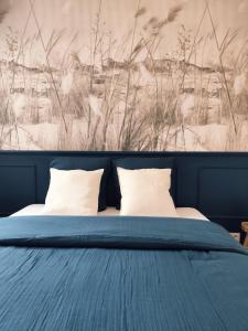 un lit avec deux oreillers et un tableau au mur dans l'établissement Appartement cosy en centre-ville, à Calais