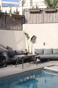 a patio with a table and couches next to a pool at וילה מעגל השמש in Poriyya Illit