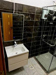 a black tiled bathroom with a sink and a shower at Book n Breeze in Nairobi