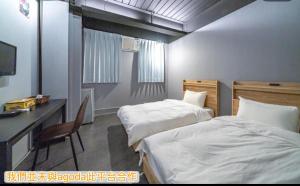 Una habitación de hotel con dos camas, un escritorio y una computadora. en 新橙居-我們未與阿狗打訂房平台合作請勿在阿狗打訂房平台訂房, en Dalin