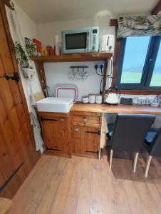 a kitchen with a desk and a sink and a microwave at Y Cwtch in Trefeglwys +9 photos