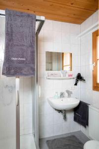 a white bathroom with a sink and a mirror at Chalet Auszeit Montafon in Bartholomäberg
