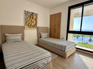 two beds in a room with a window at Sea View Apartment & Swimming Pool in Sidi Bouqnadel +10 photos