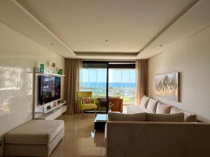 a living room with a couch and a television at Sea View Apartment & Swimming Pool in Sidi Bouqnadel
