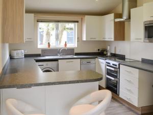 Una cocina con gabinetes blancos y un fregadero. en Ocean Glade - Uk32963, en Corton