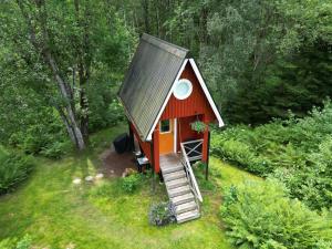 a small red house with a metal roof at Small Cabin With Outdoor Kitchen By Forest Stream in Trollhättan