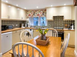 een keuken met een houten tafel met stoelen en een vaas erop bij Baldowrie Lodge in Ardler