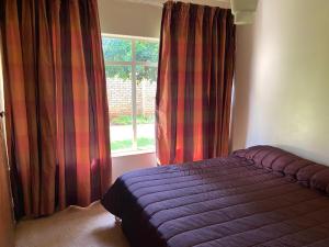 a bedroom with a purple bed in front of a window at Highway Haven in Stilfontein +4 photos