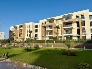a large apartment building with a lawn in front of it at Sea View Apartment & Swimming Pool in Sidi Bouqnadel