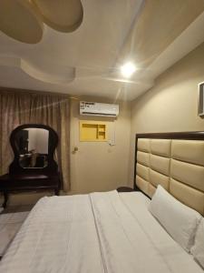 a bedroom with a large bed and a mirror at Roaa Apartments in Al Qunfudhah