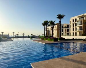 a swimming pool in front of a building with palm trees at Sea View Apartment & Swimming Pool in Sidi Bouqnadel