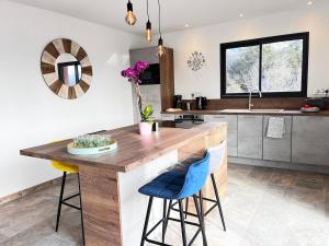 a kitchen with a large wooden island with blue bar stools at Maison neuve Jacuzzi et Piscine Haut de Gamme in Vallon-Pont-dʼArc